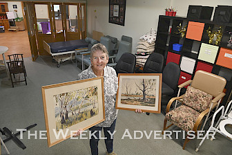 Ann Falkingham with art works by Dr Alister Hinchley up for auction and raffle prizes to raise money for Allambi units in Dimboola.